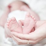 Tender photo of a mother's hands holding her newborn's feet, symbolizing love and care.