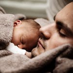 A touching close-up of a father and his baby peacefully napping together.