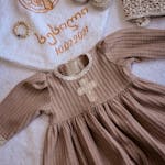 Top view of dress hat and small baby bootees on towel with inscription and cross prepared for christening