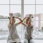 Two happy children playing with books, embodying the joy of learning together.